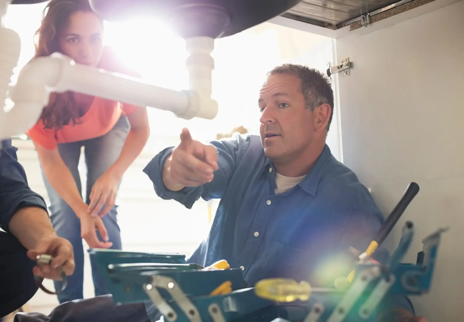 Plumber explains under-sink repair to homeowner