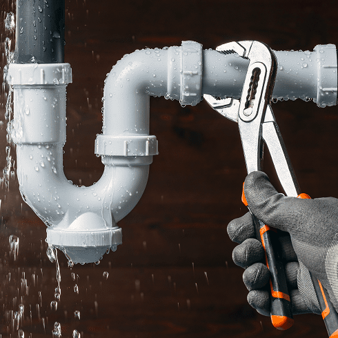 Plumber fixing leaking pipe with wrench