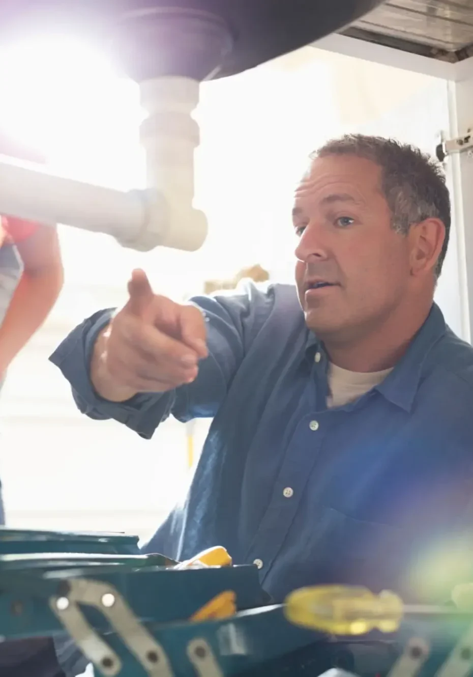 Plumber explains under-sink repair to homeowner
